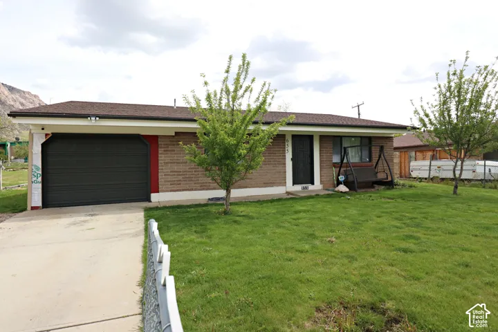 Ranch-style home with brick siding, concrete driveway, a front lawn, and a garage
