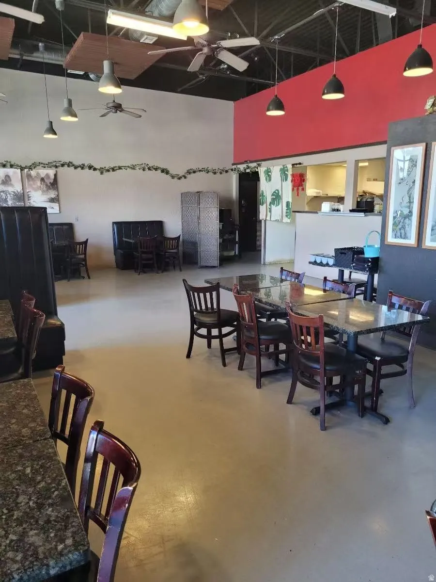 Dining area featuring concrete flooring, a ceiling fan, and a high ceiling