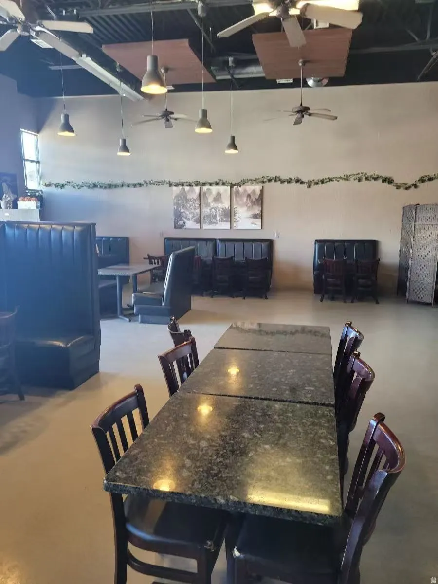 Dining space with ceiling fan, finished concrete flooring, and a high ceiling