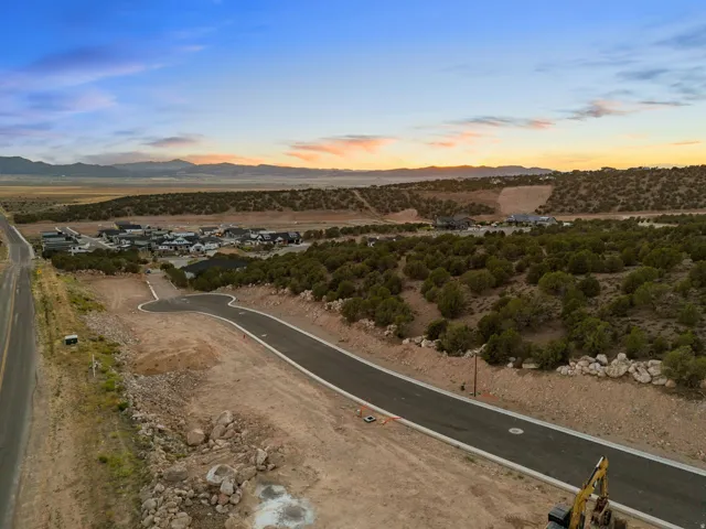 Developing residential area featuring a paved road, established housing, and natural landscaping