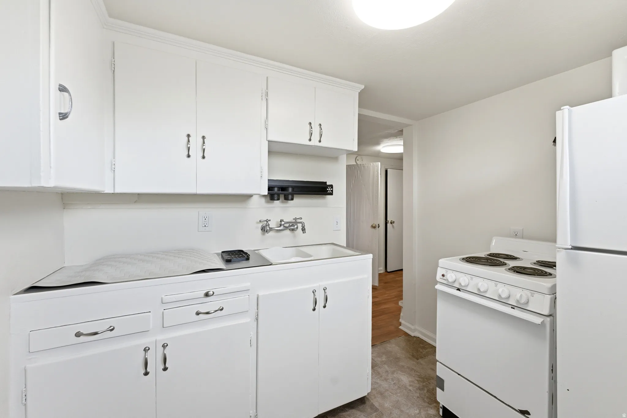 Kitchen with white appliances, white cabinetry, and light countertops