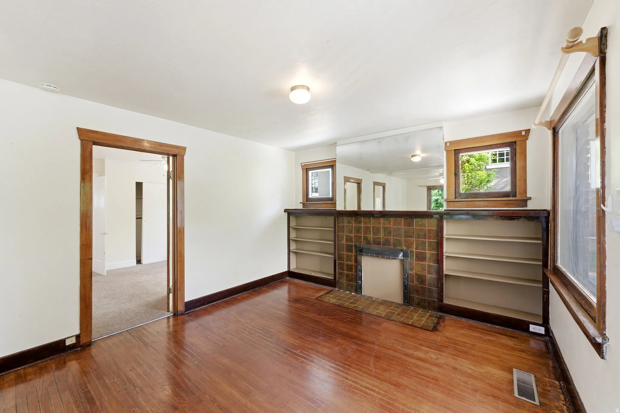 Unfurnished living room featuring dark wood finished floors and a tile fireplace