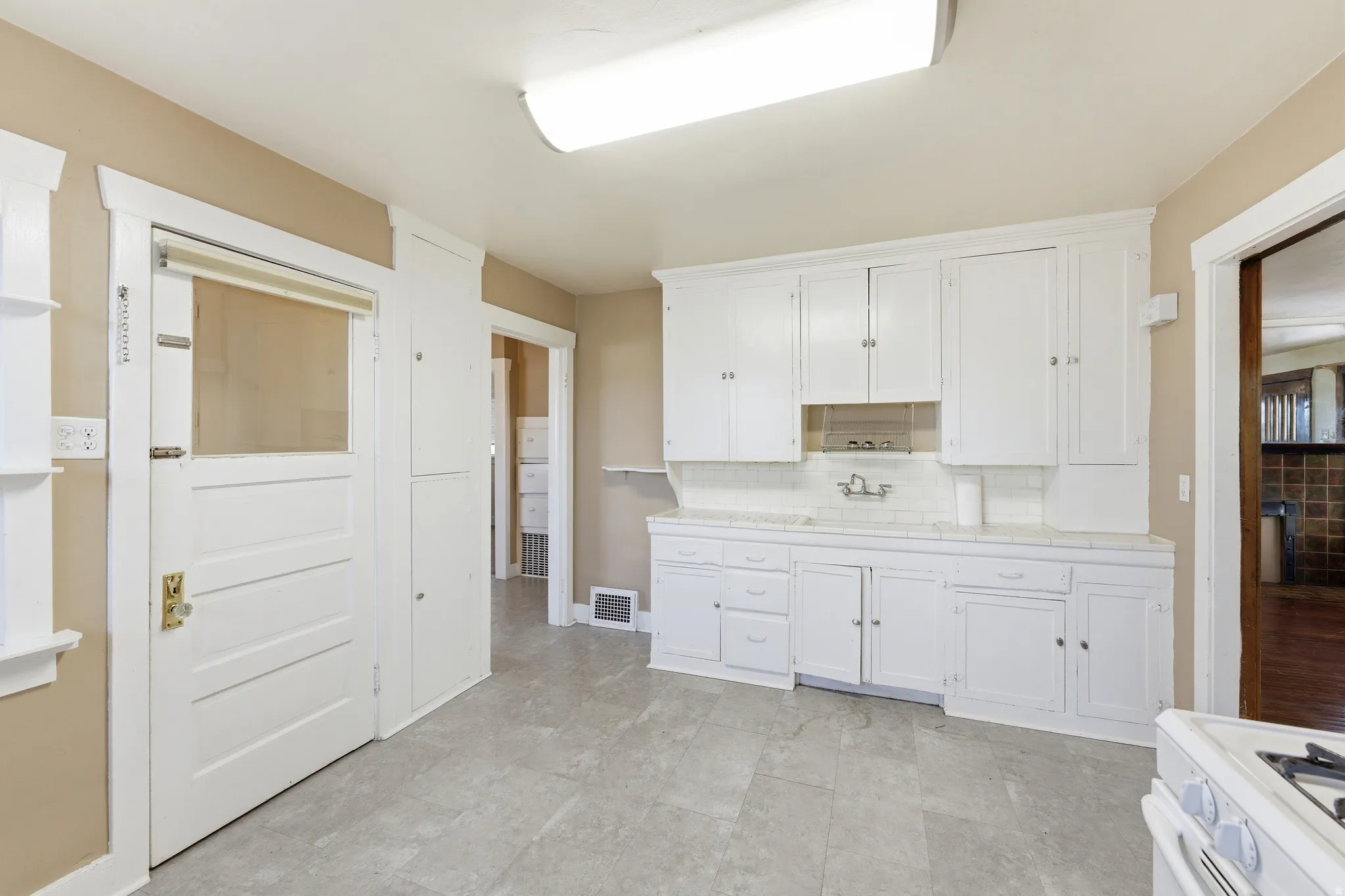 Kitchen featuring white cabinets, white range with gas cooktop, light countertops, and backsplash