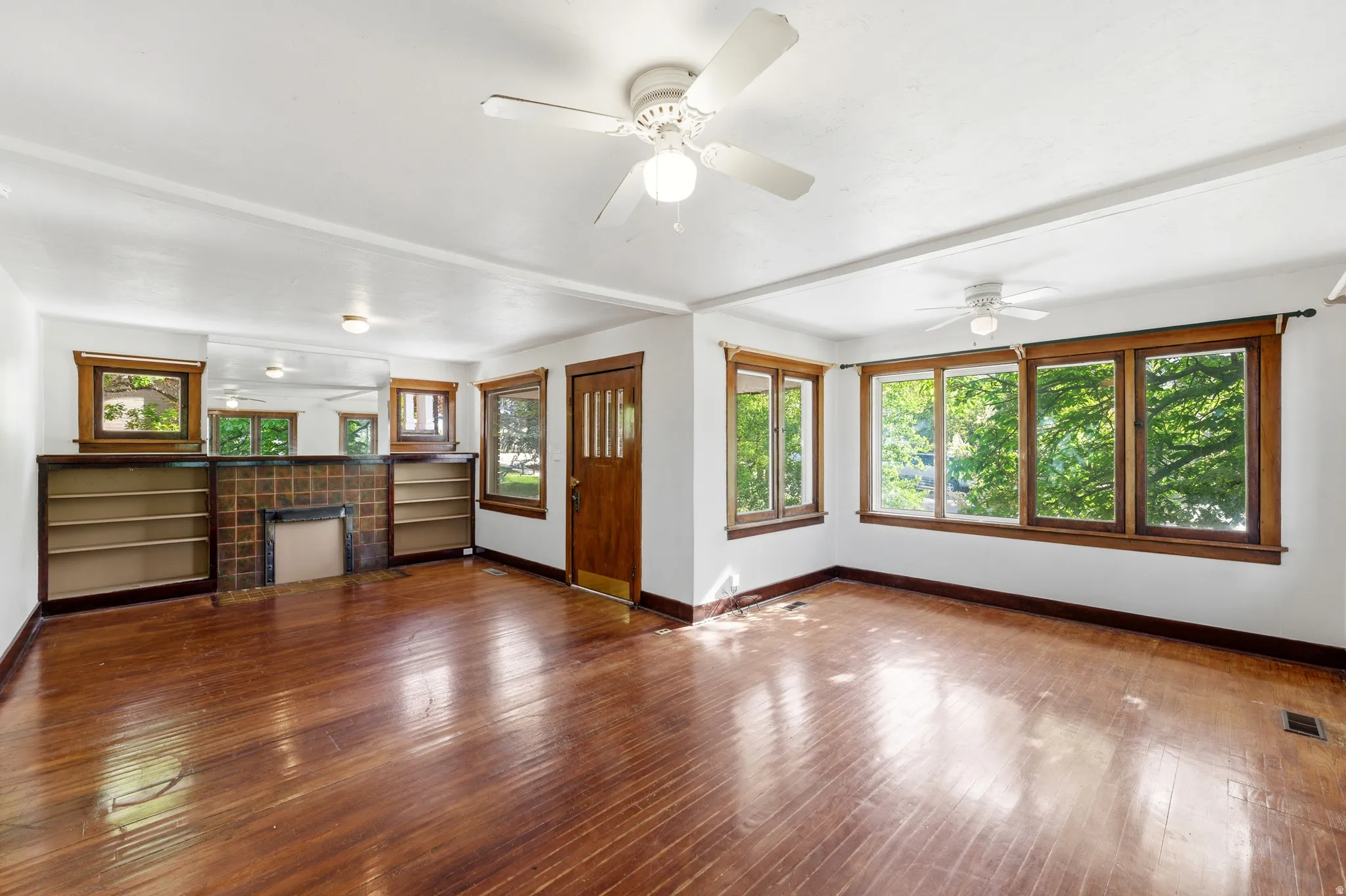 Unfurnished living room featuring dark wood finished floors, a ceiling fan, and a tiled fireplace