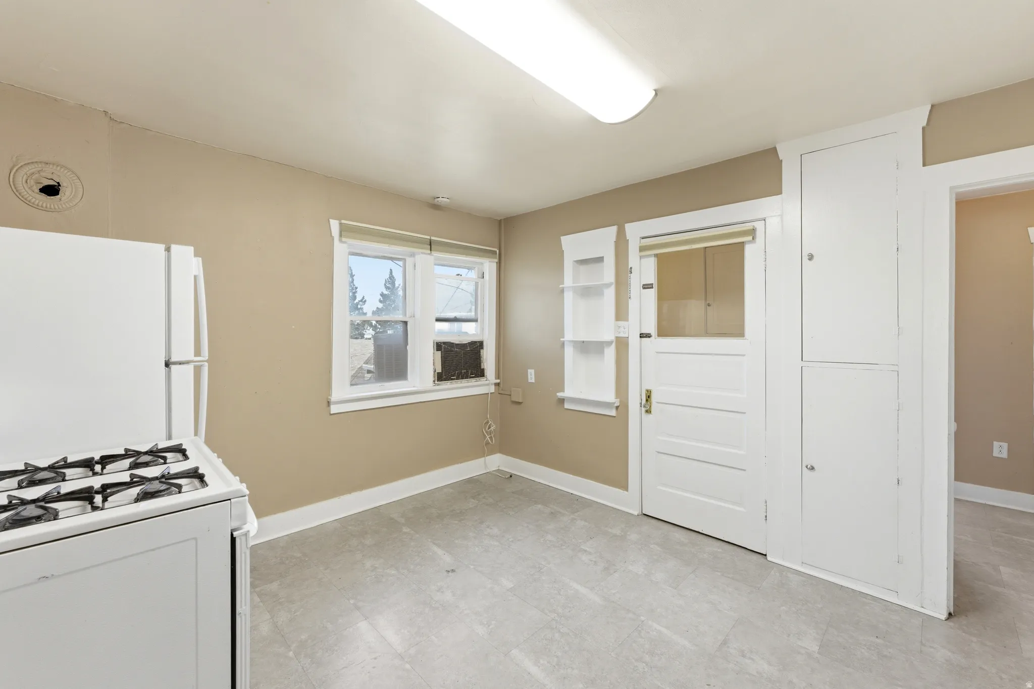 Kitchen featuring white appliances, light flooring, and white cabinetry