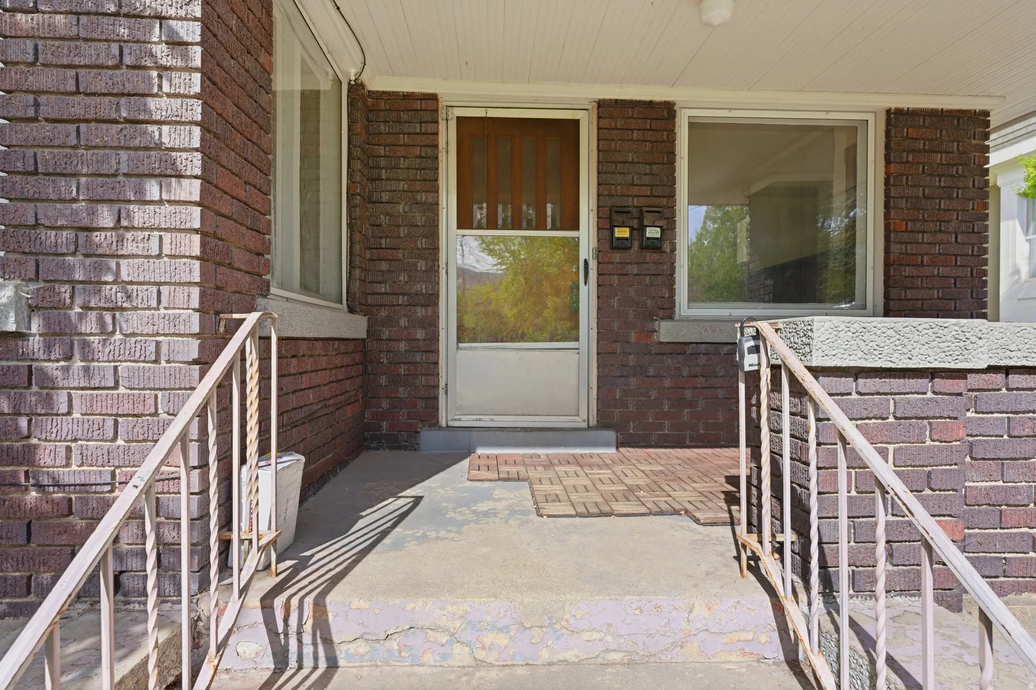 View of exterior entry with brick siding and a porch
