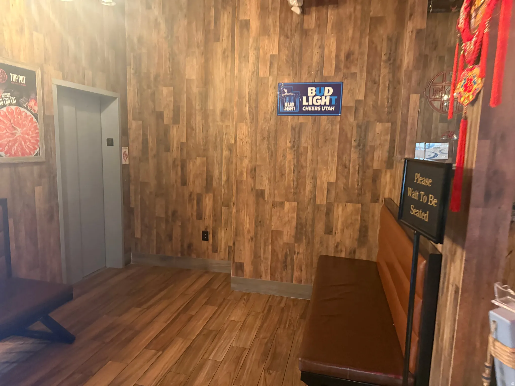 Hallway featuring dark wood-style flooring, wood walls, and elevator