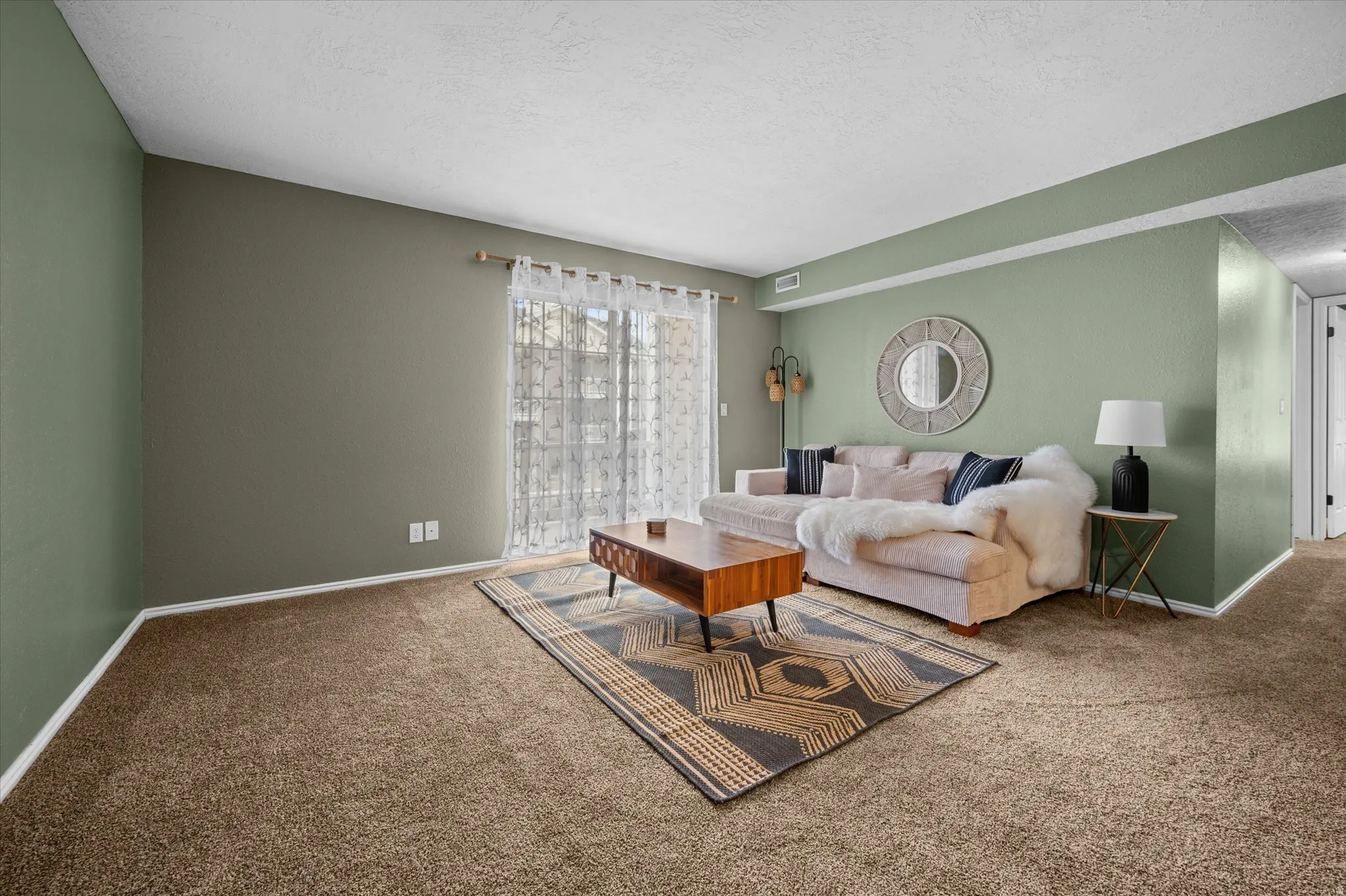 Carpeted living room with a textured ceiling and baseboards