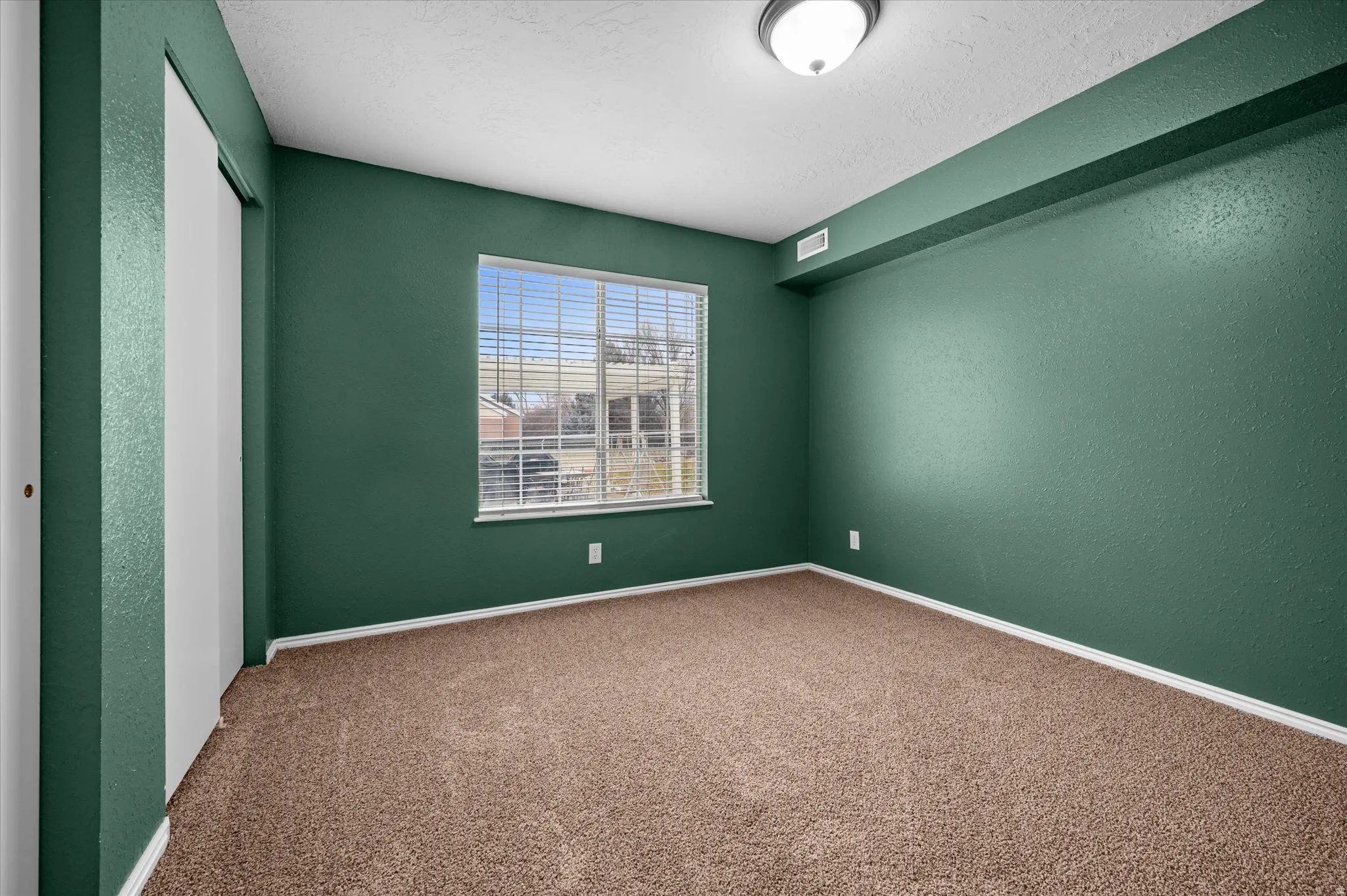 Carpeted empty room featuring a textured wall
