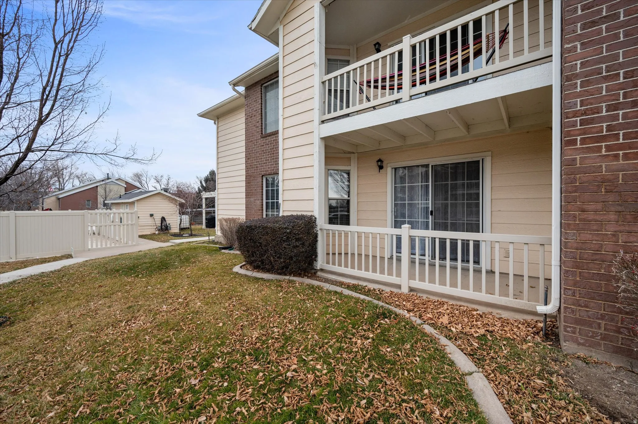View of property exterior featuring a balcony, brick siding, and a gate