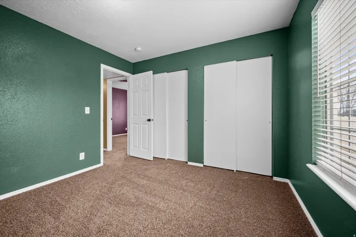 Unfurnished bedroom with two closets, carpet flooring, a textured wall, and a textured ceiling
