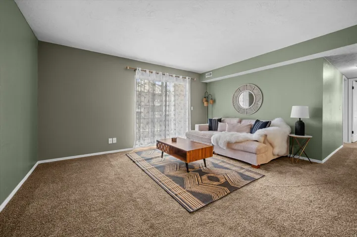 Carpeted living room with a textured ceiling and baseboards