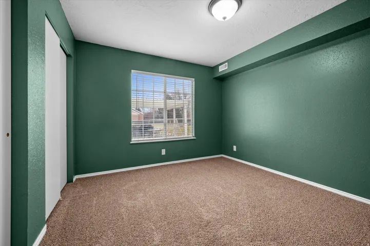 Carpeted empty room featuring a textured wall