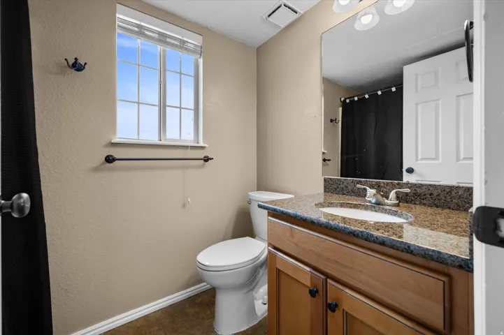 Bathroom with a textured wall, vanity, a shower with curtain, and dark tile patterned floors