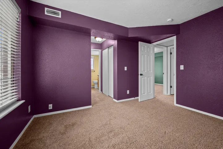 Unfurnished room featuring a textured wall, light carpet, healthy amount of natural light, and a textured ceiling
