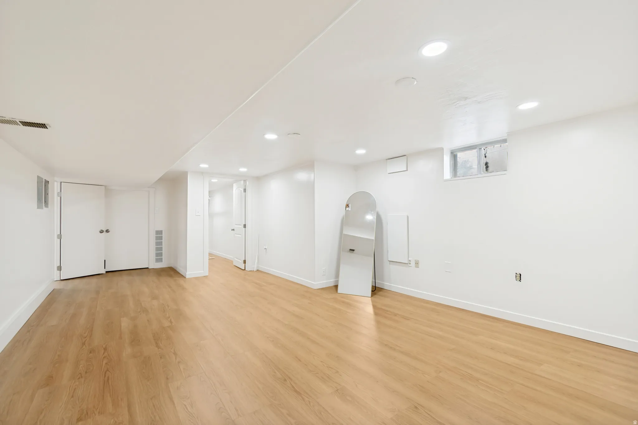 Basement featuring light wood-type flooring, recessed lighting, and arched walkways
