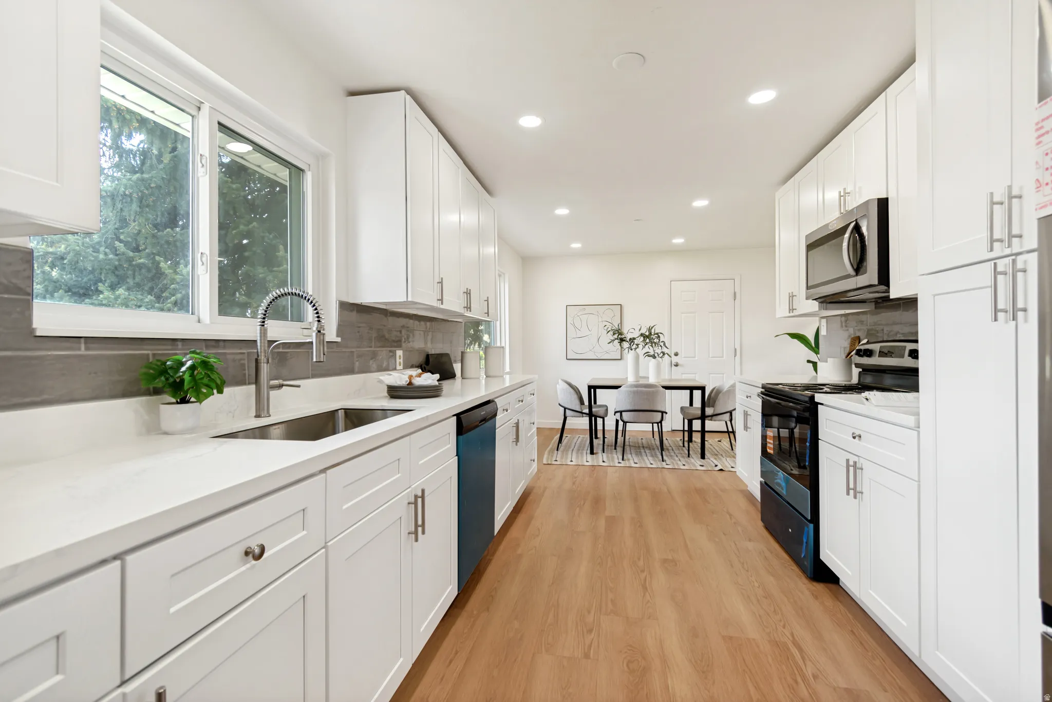 Kitchen featuring black electric range, white cabinets, light wood-style floors, recessed lighting, and light stone counters