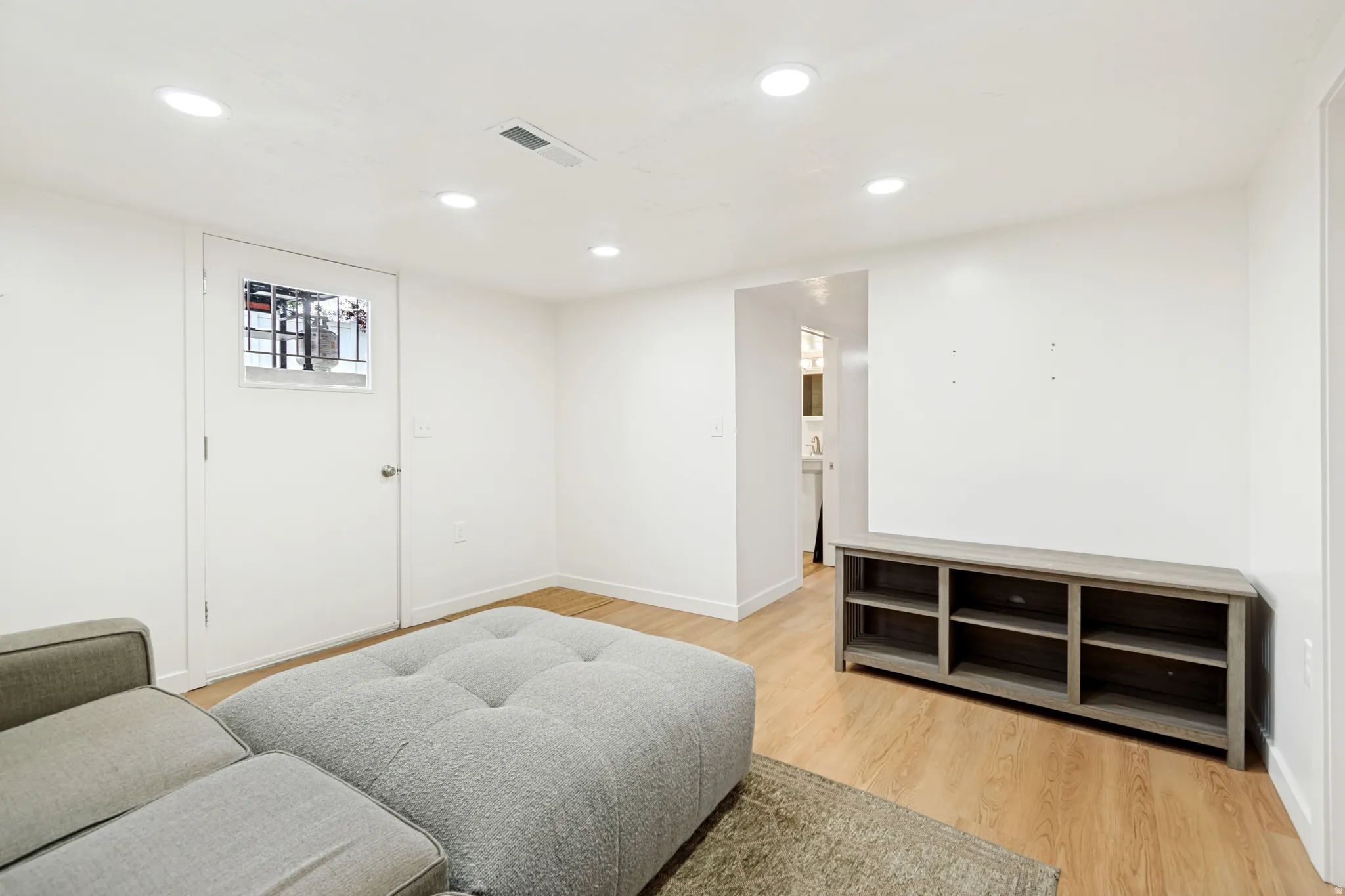 Living area with light wood-style flooring and recessed lighting