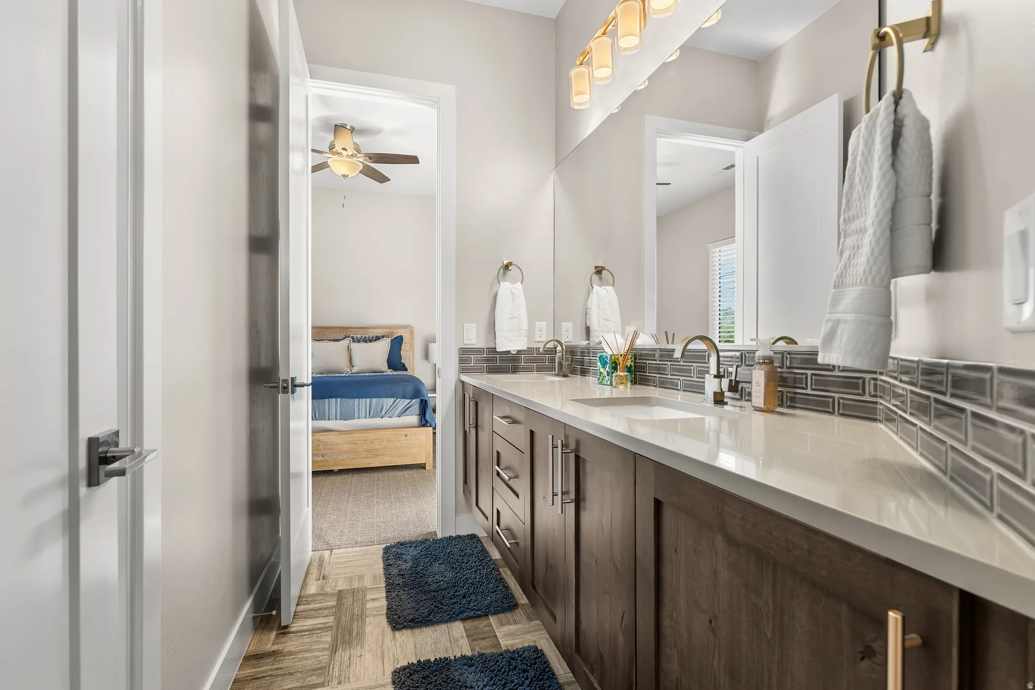 Ensuite bathroom featuring double vanity, light wood finished floors, and a ceiling fan