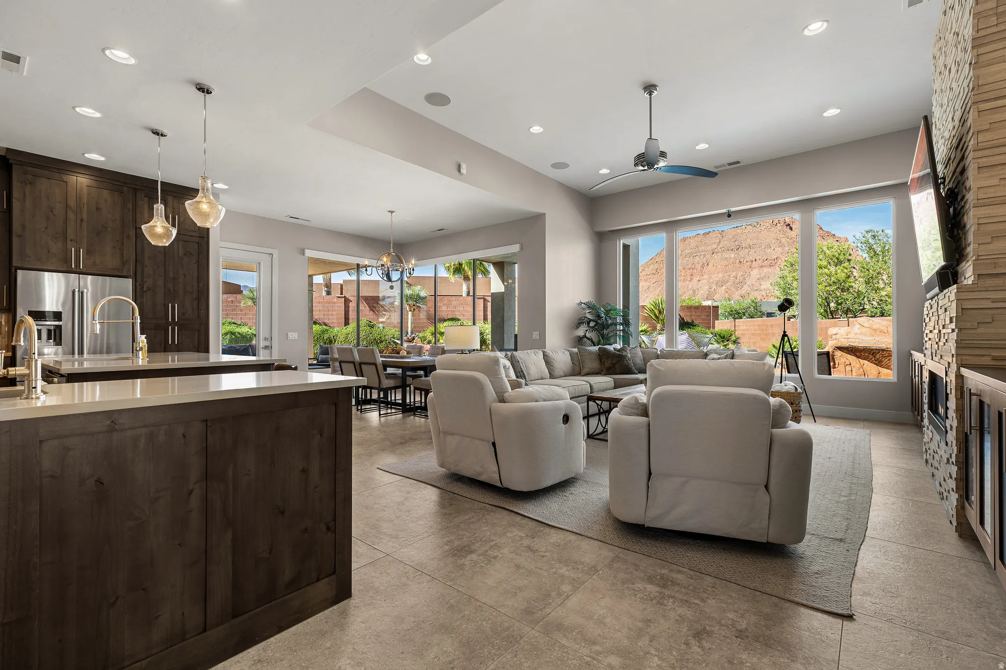 Living room with a stone fireplace, ceiling fan, and a chandelier