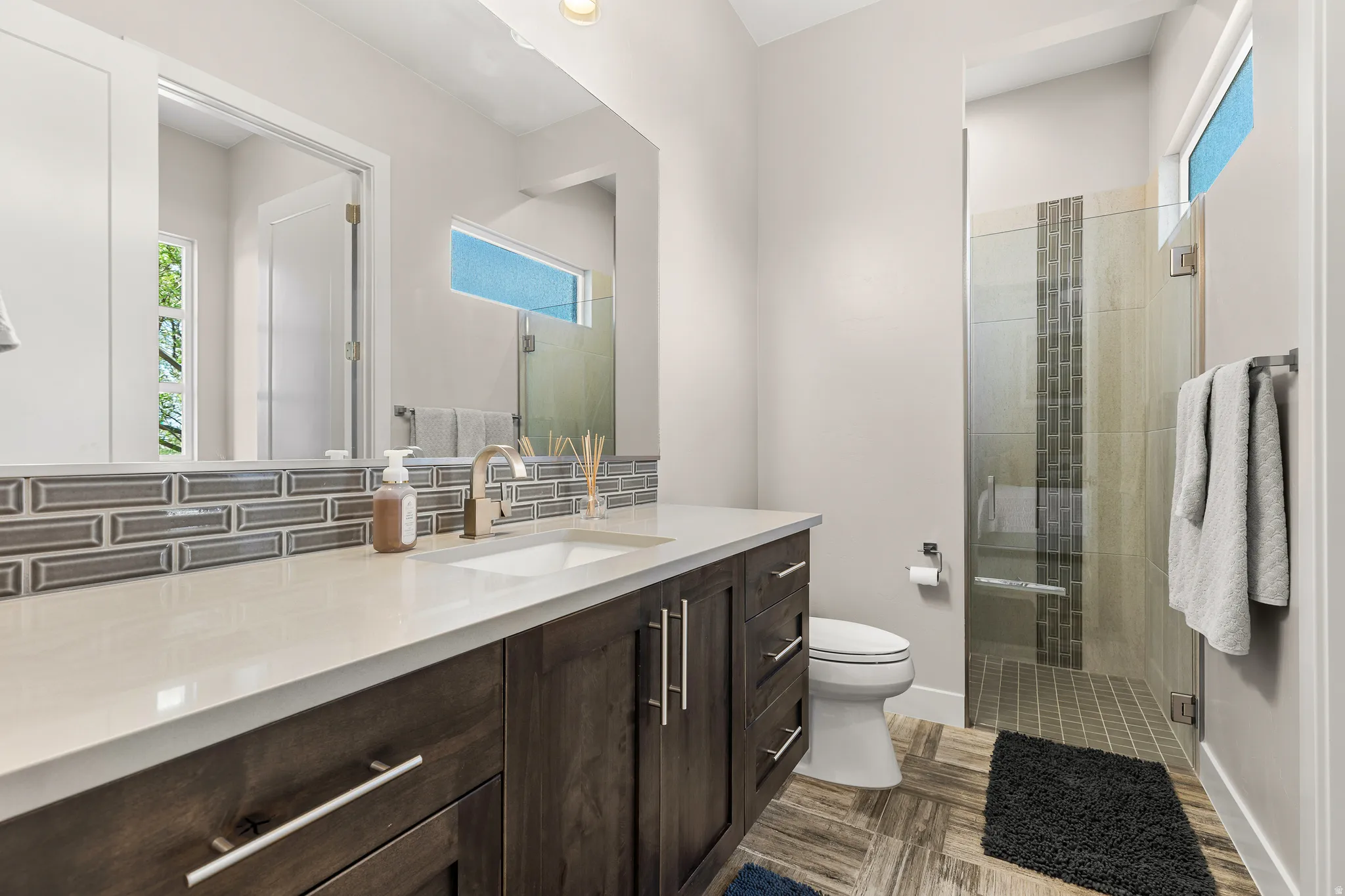 Bathroom with a stall shower, vanity, and decorative backsplash