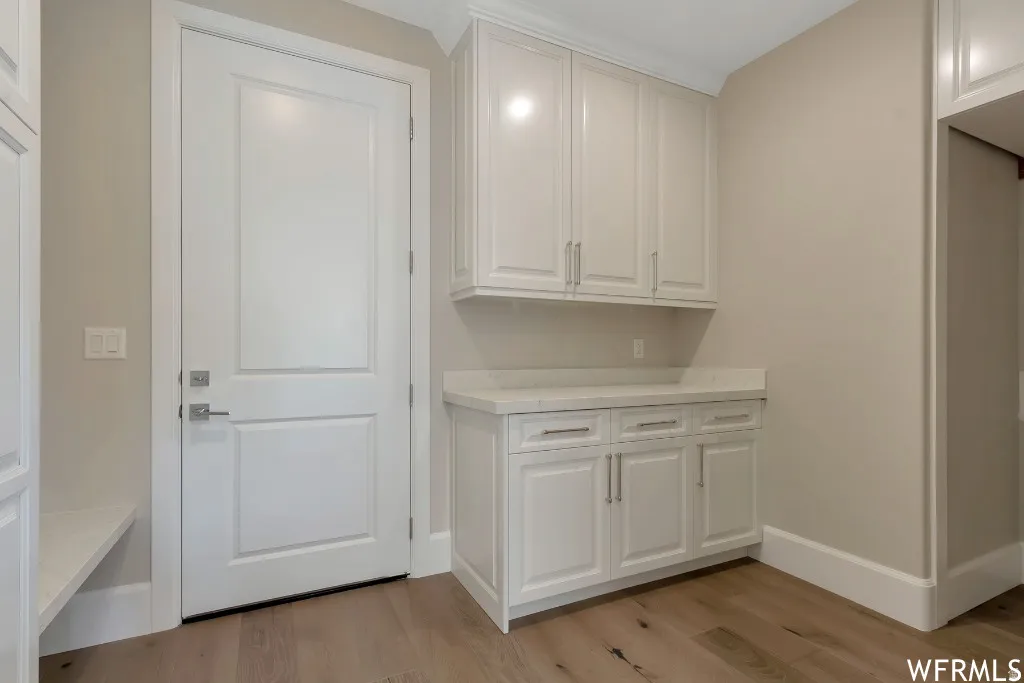 Laundry area with baseboards and light wood-style floors