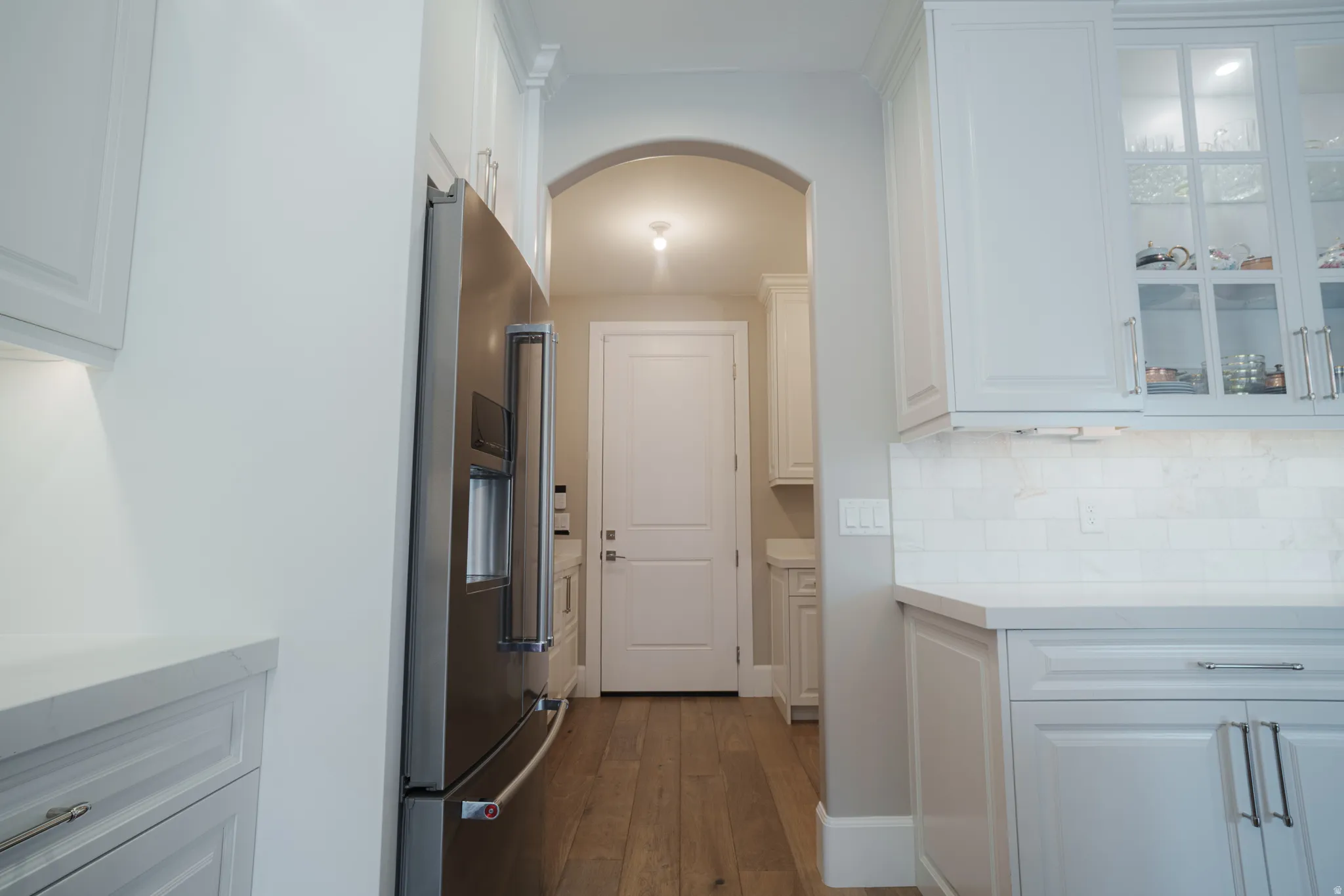 Doorway with arched walkways and hardwood / wood-style flooring