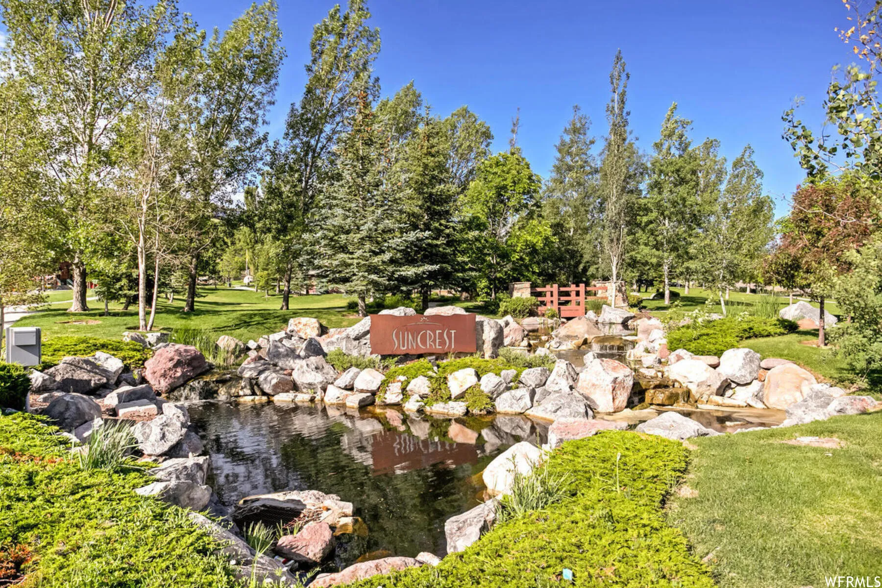 View of green lawn featuring a small pond and view of scattered trees