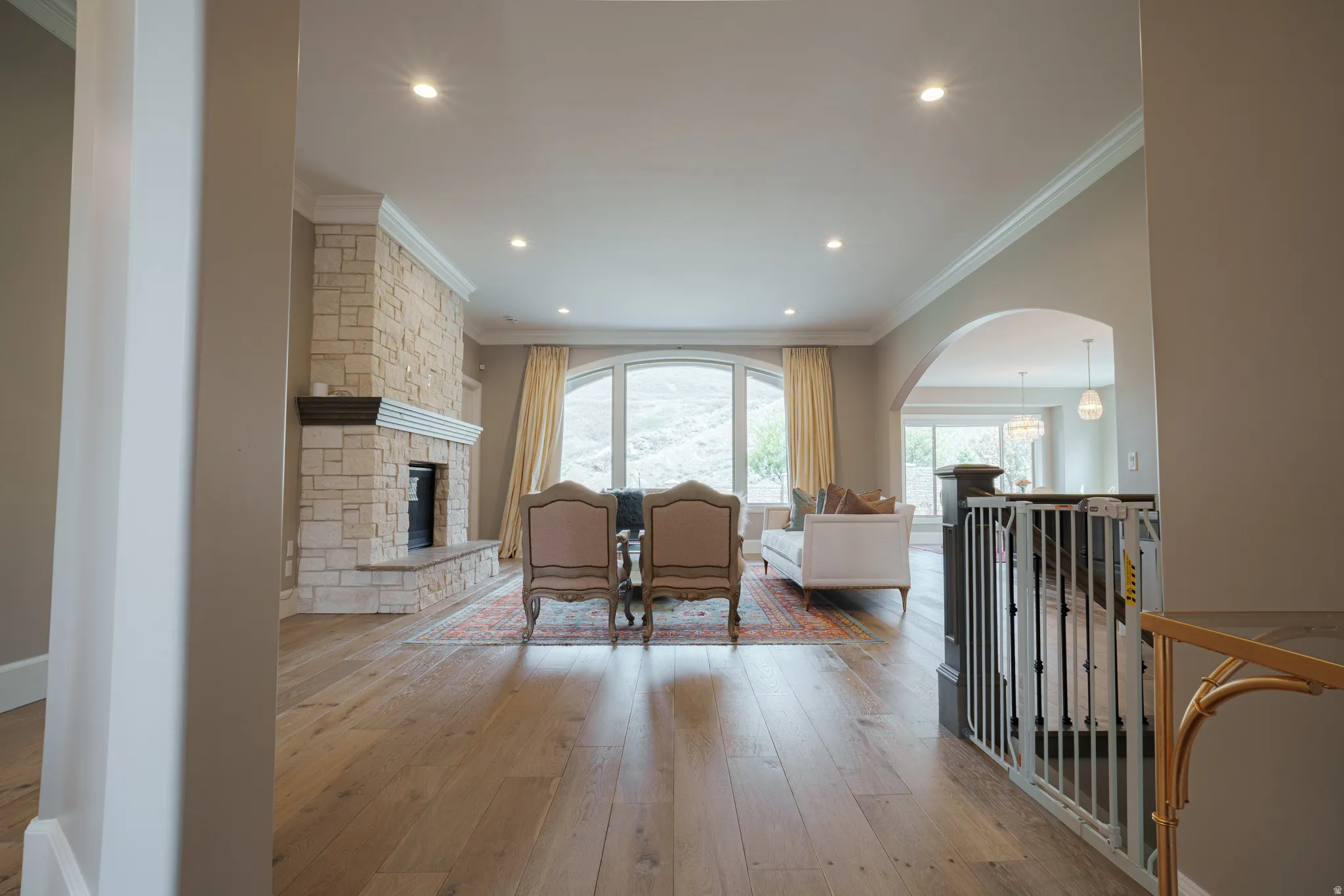Living room with arched walkways, ornamental molding, light wood-style floors, a fireplace, and recessed lighting