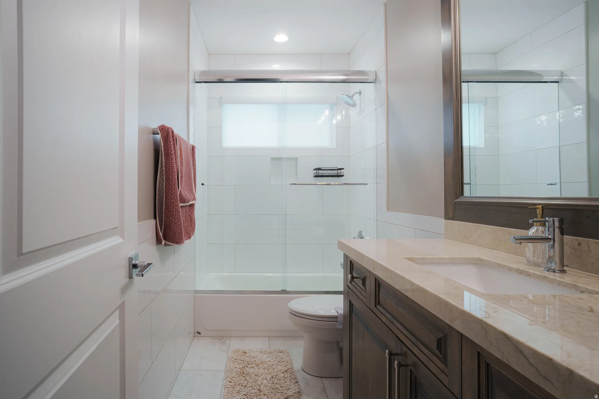 Bathroom with vanity and combined bath / shower with glass door
