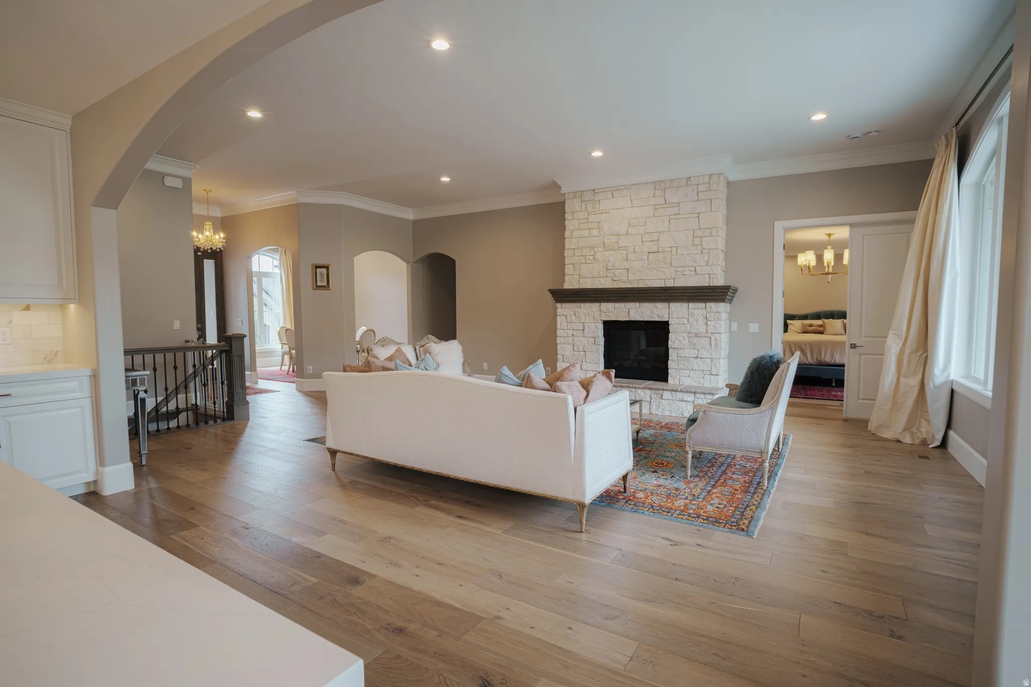 Living room featuring hanging lights, light wood-type flooring, a fireplace, and ornamental molding