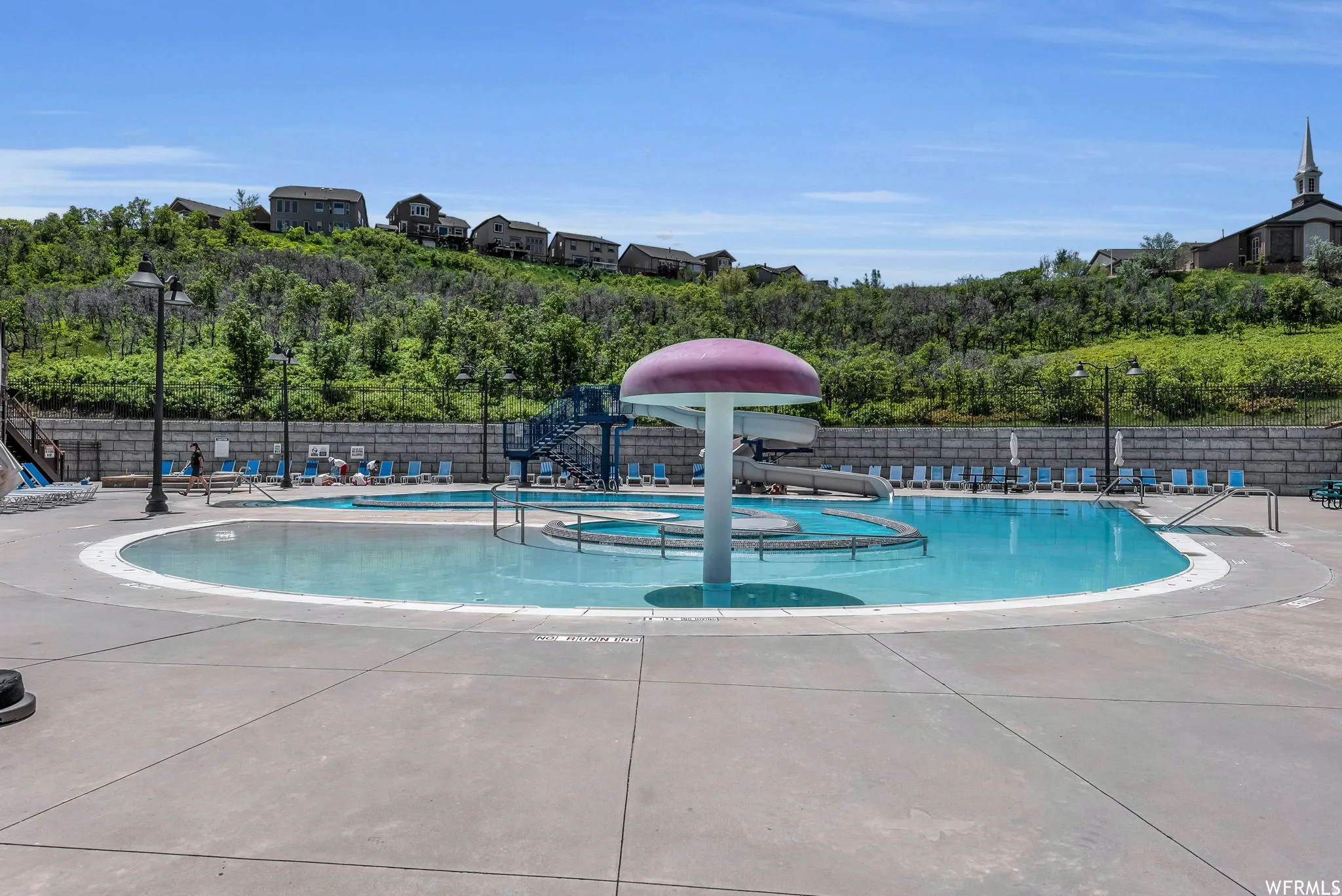 Community pool featuring a water slide and a patio