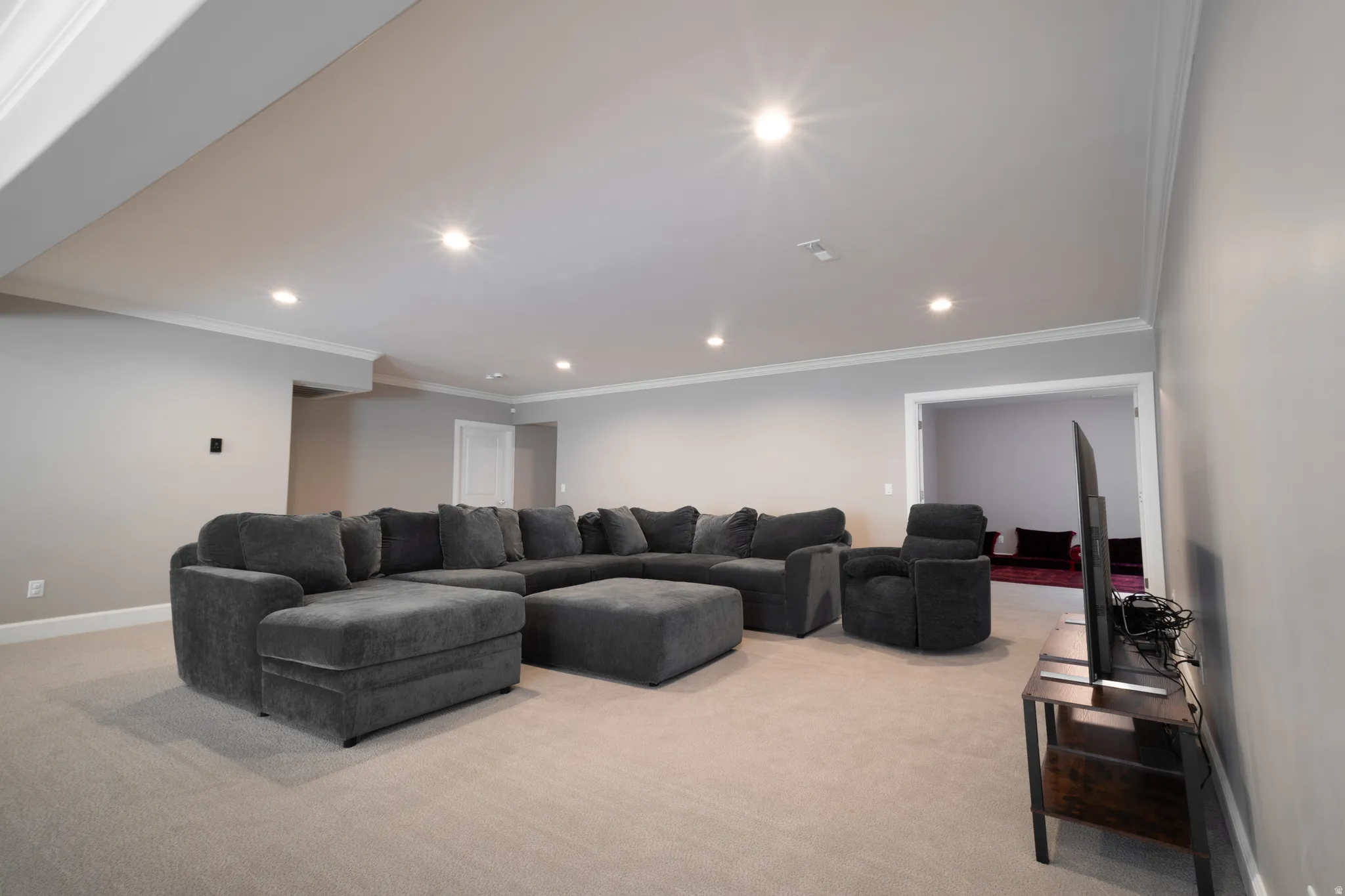 Living area with crown molding, light colored carpet, and recessed lighting