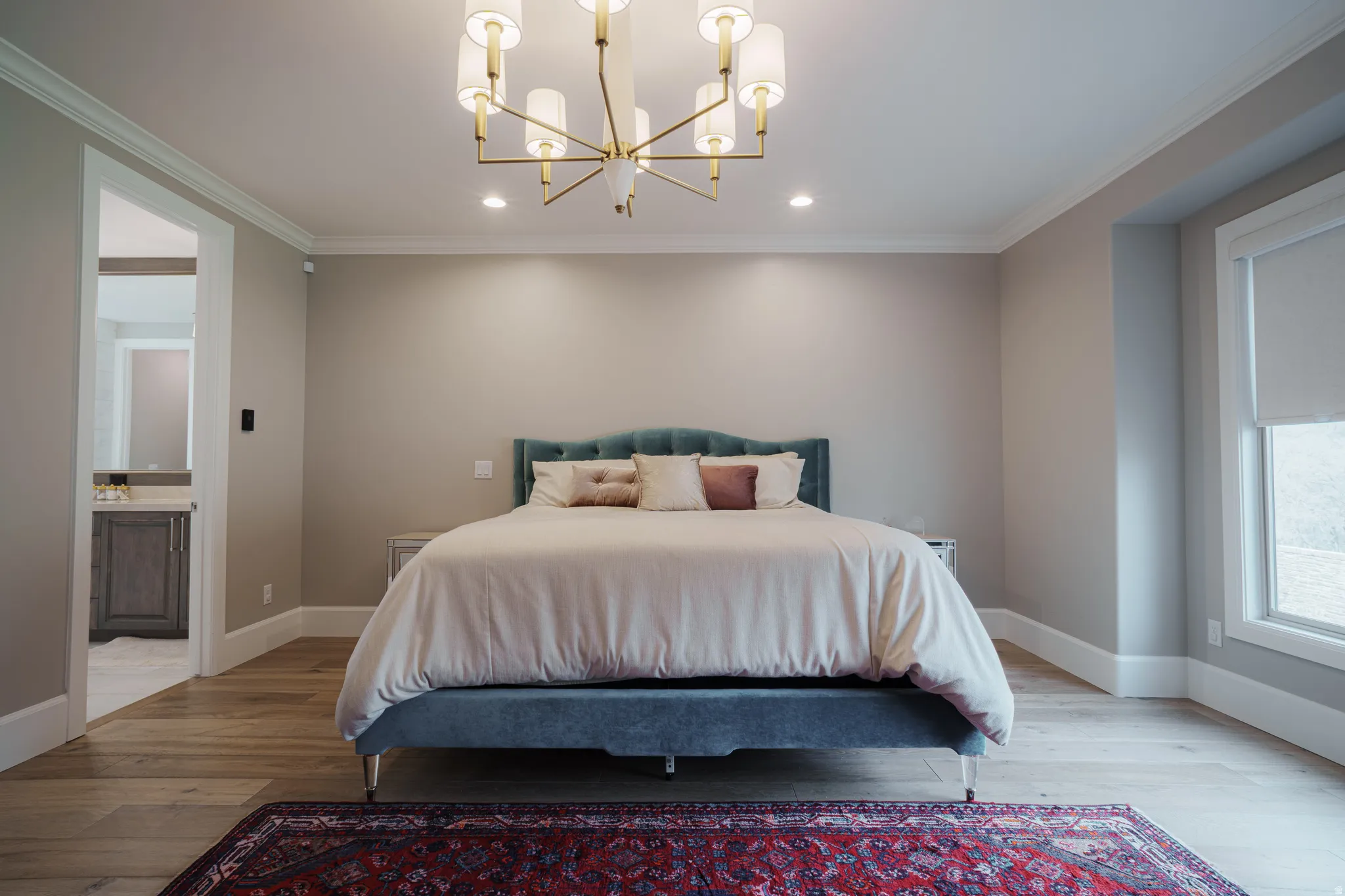 Bedroom with hardwood / wood-style floors, ornamental molding, a chandelier, and ensuite bath