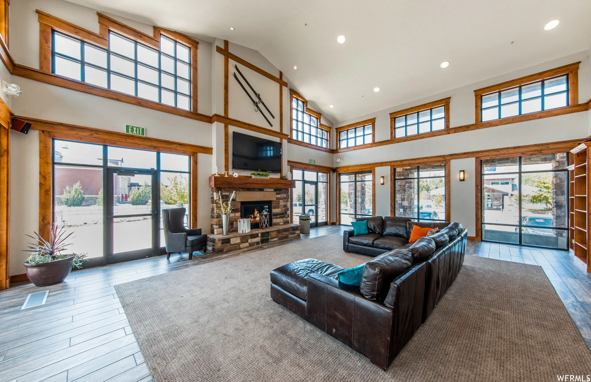 Living area with a stone fireplace, light wood-style floors, recessed lighting, and lofted ceiling