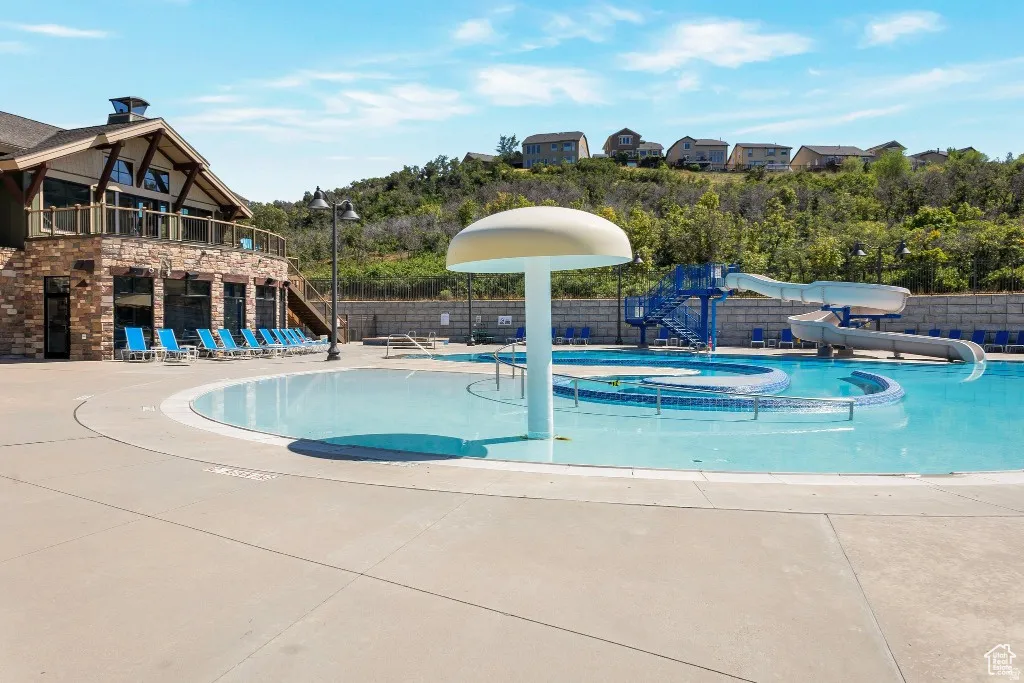 Community pool featuring a water slide, a patio, a jacuzzi, and a water play area