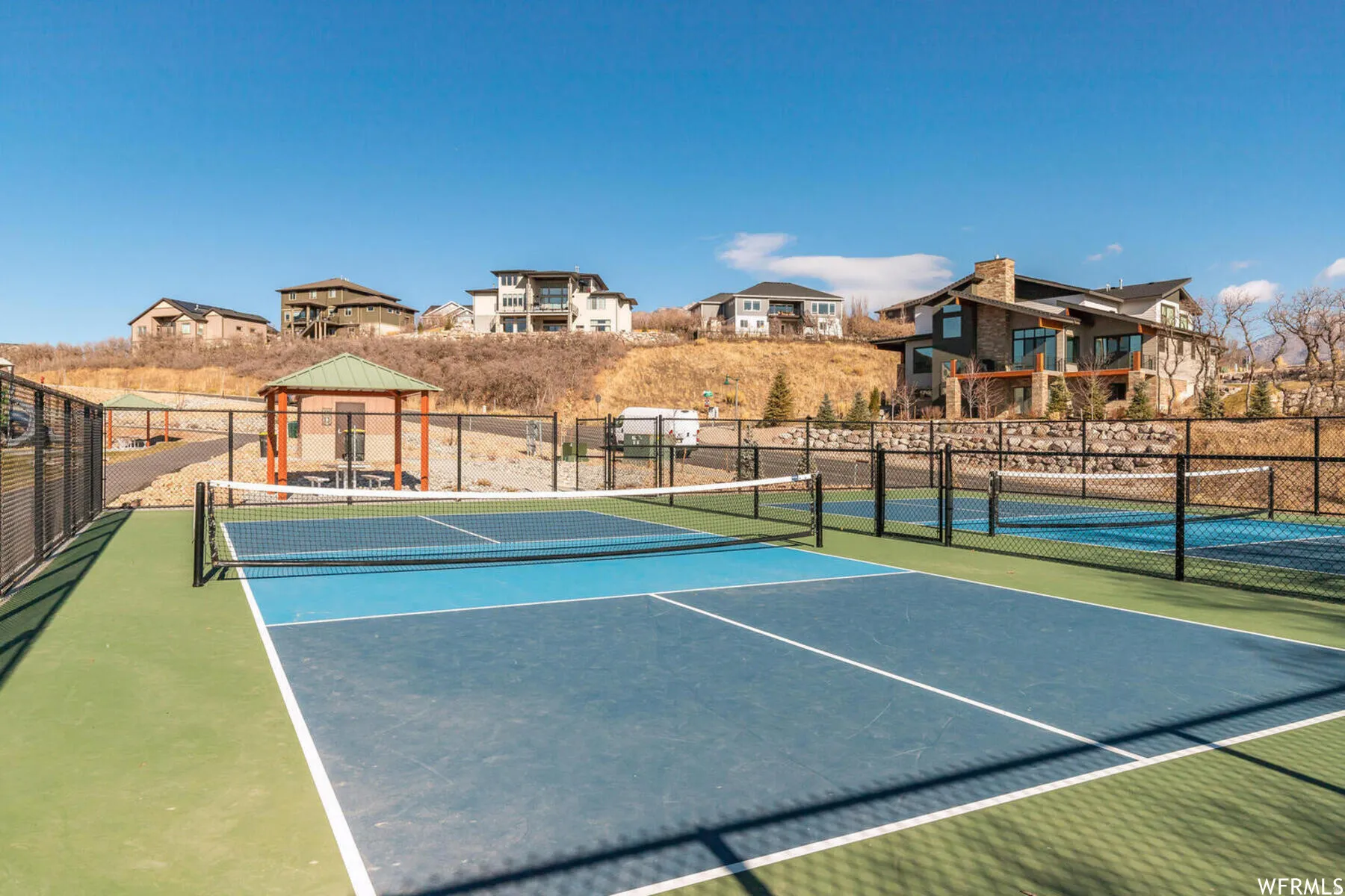 View of tennis court with a gazebo and a residential view
