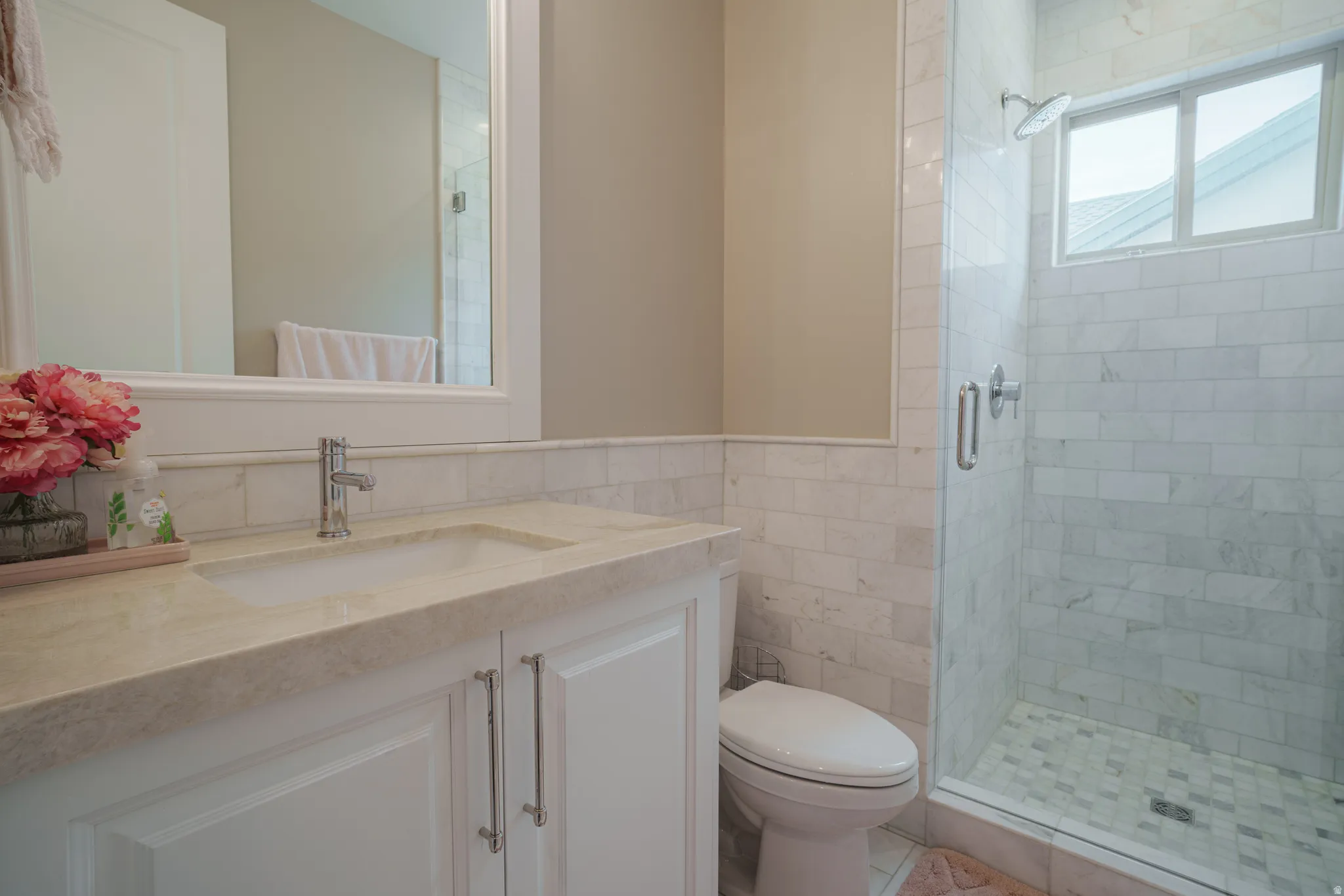 Full bathroom with tile walls, vanity, a shower stall, and wainscoting