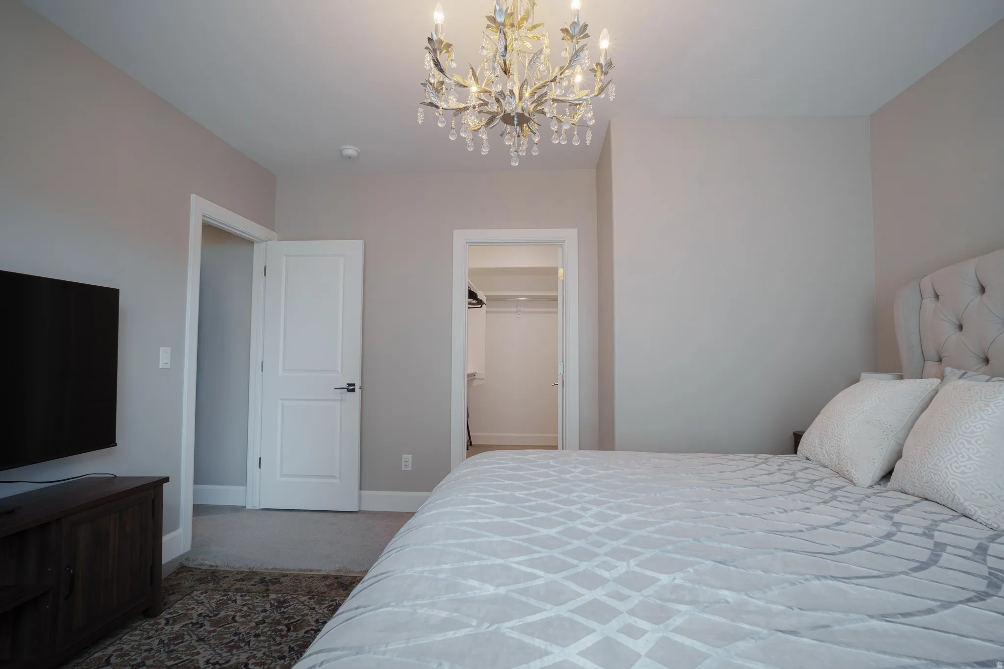 Carpeted bedroom featuring a walk in closet and suspended lighting
