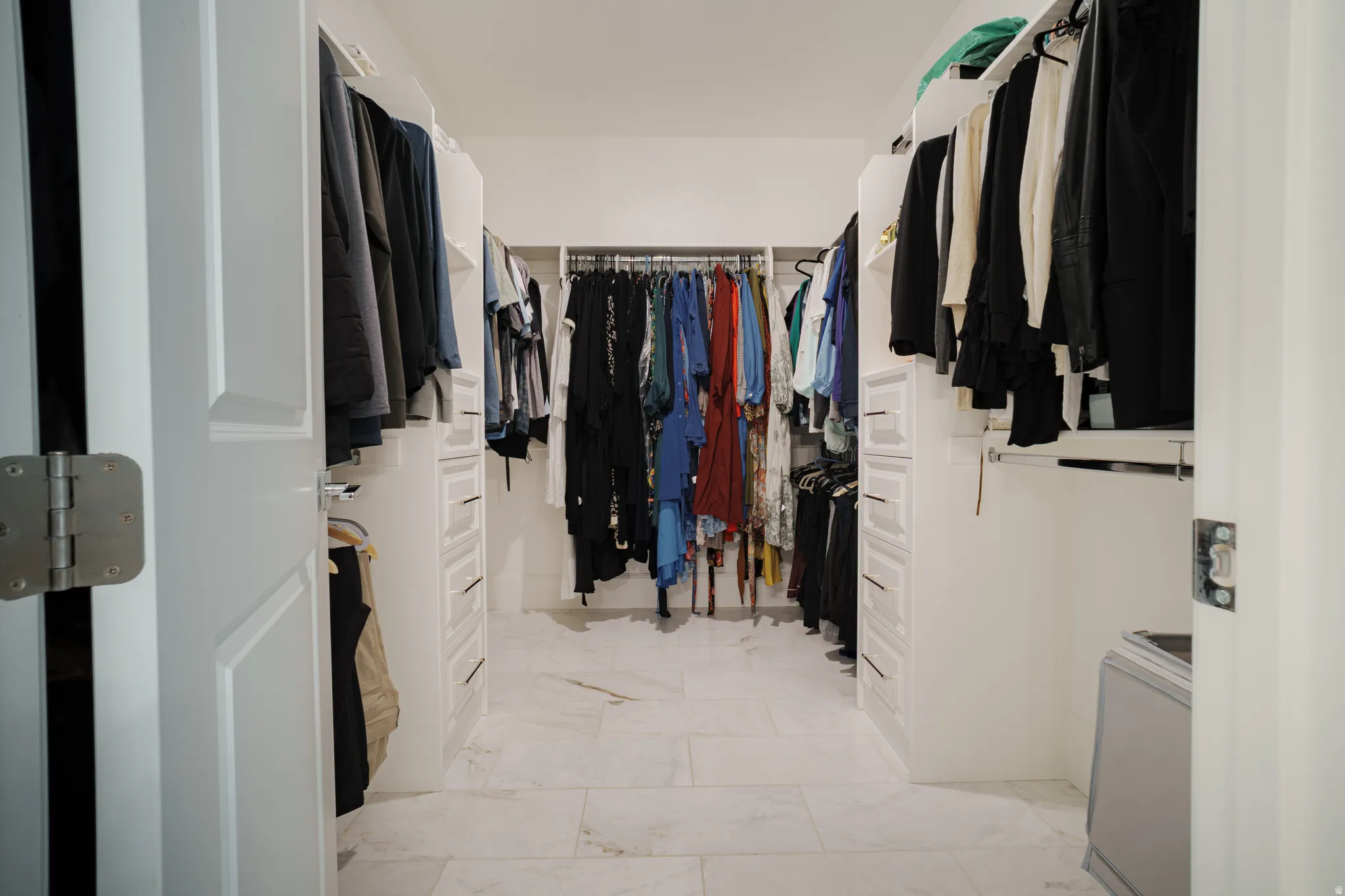 Walk in closet featuring light marble finish flooring