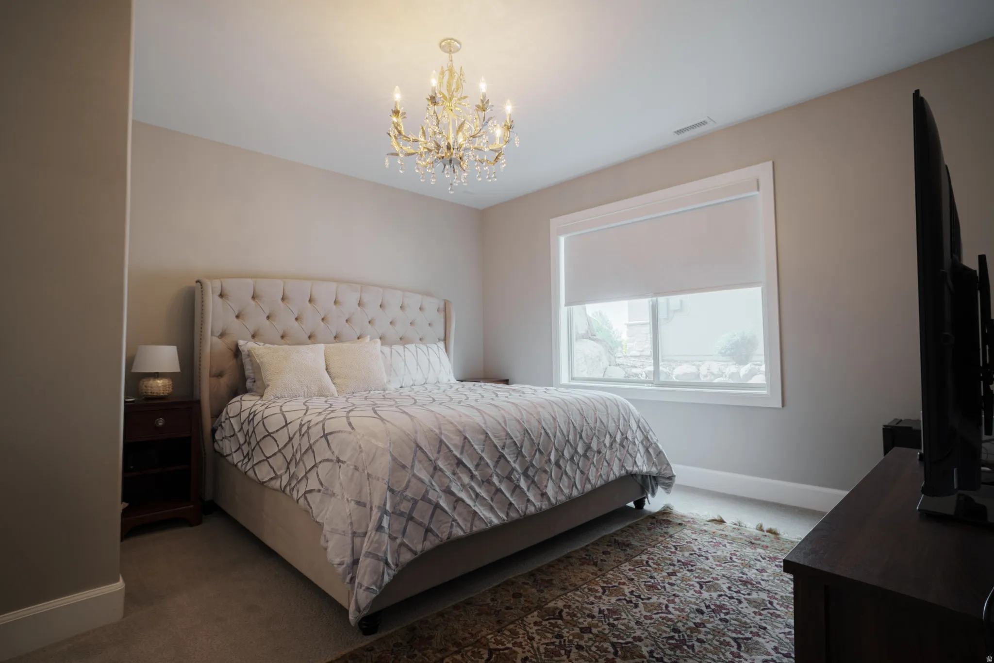 Carpeted bedroom with baseboards and a chandelier