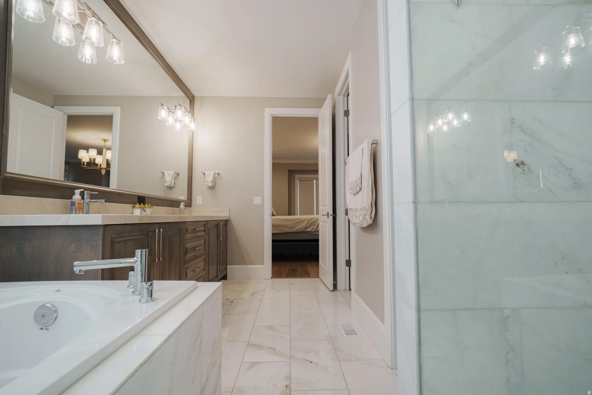 Bathroom with connected bathroom, vanity, a bath, light marble finish floors, and a shower
