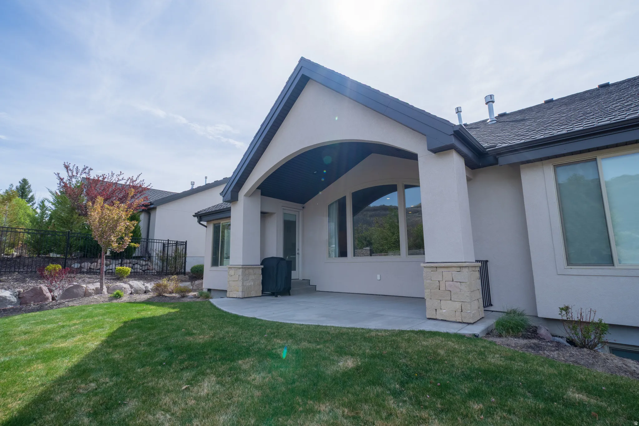 Rear view of house with stucco siding, stone siding, and a patio area
