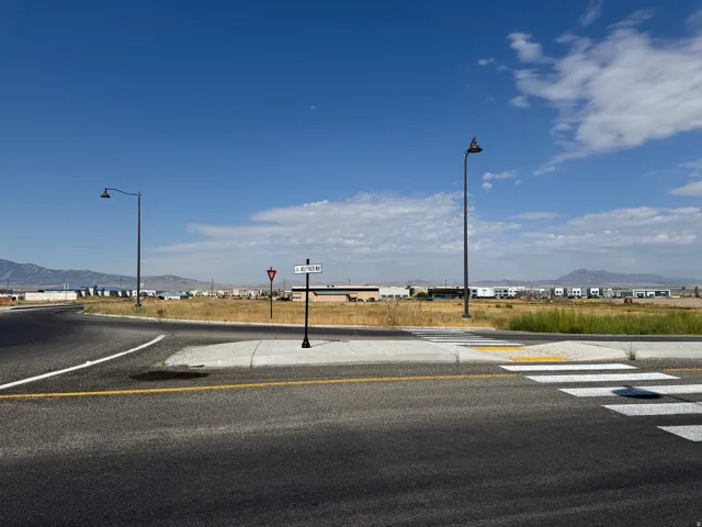 View of asphalt street with a mountain view, street lights, and curbs