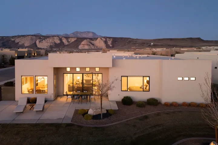 Rear view of property with stucco siding, a patio, outdoor dining space, and a mountain view