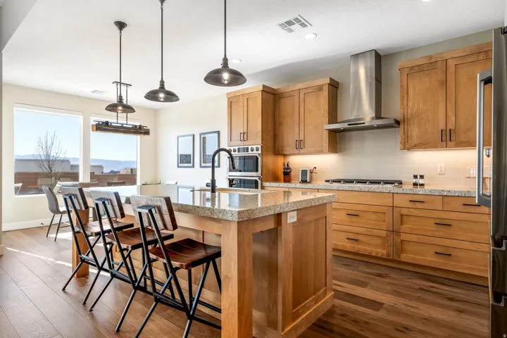 Kitchen with a kitchen island with sink, backsplash, dark wood-style flooring, a kitchen bar, and decorative light fixtures