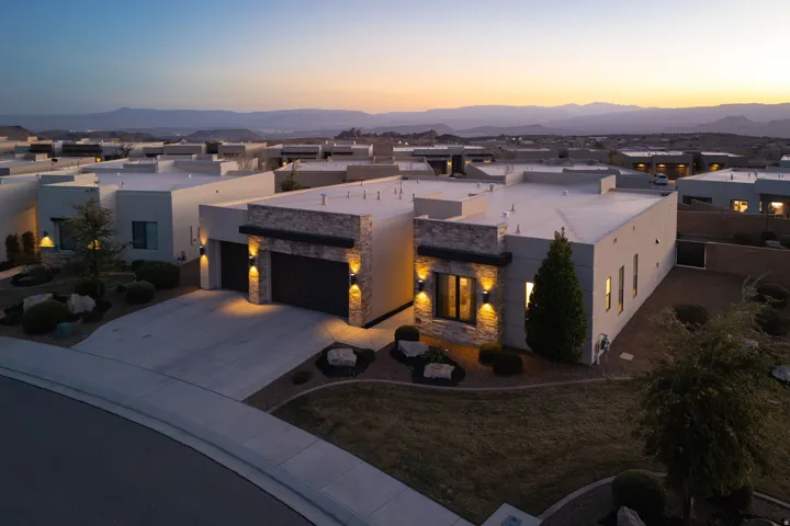 Modern home featuring a garage, a patio area, stone siding, and a residential view