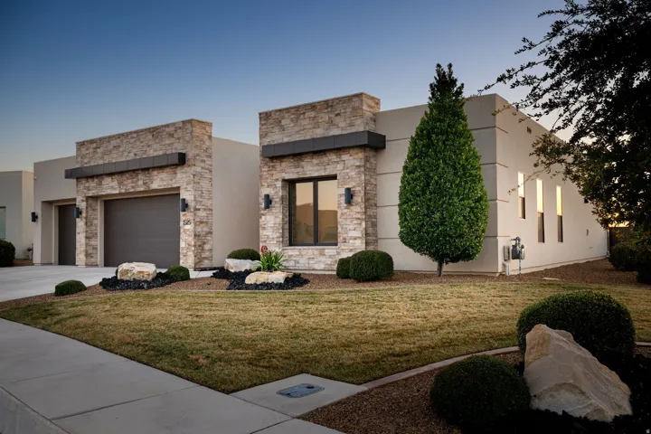 Contemporary home featuring a front lawn, stucco siding, an attached garage, concrete driveway, and stone siding