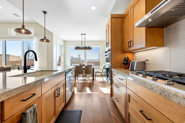 Kitchen featuring dark wood finished floors, pendant lighting, stainless steel appliances, backsplash, and wood finish cabinetry