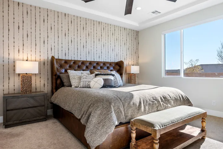 Bedroom with carpet floors, ceiling fan, an accent wall, and wallpapered walls